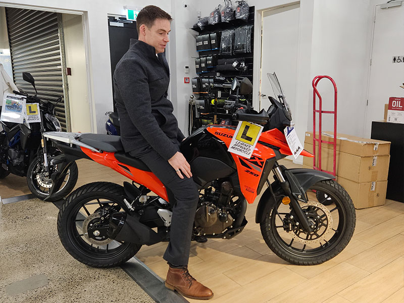 A tall man sitting on the Suzuki V-Strom 250SX.