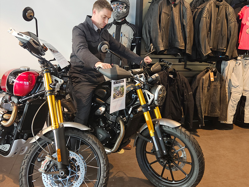 A tall man sitting on the Triumph Scrambler 400 X.